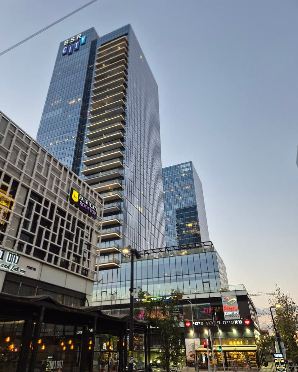 מגדלי ב.ס.ר סיטי בפתח תקווה עם השלט B.S.R CITY בראש המגדל, מבט מהרחוב בשעת ערב